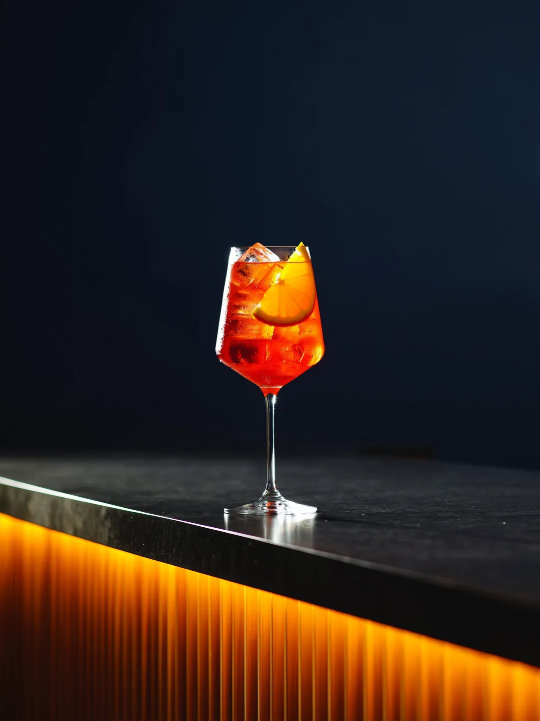 Aperol Spritz in een wijnglas op een donkere bar