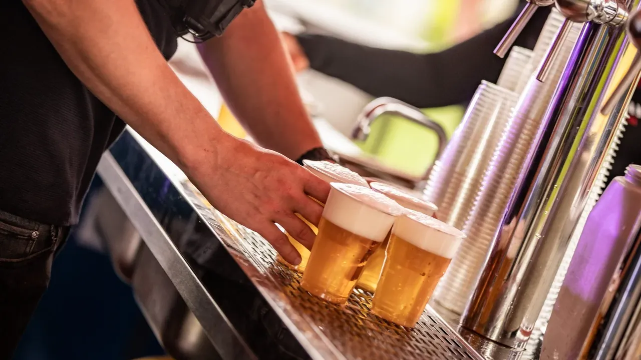 Een bartender zet getapte drankjes op de bar van een festivalbar